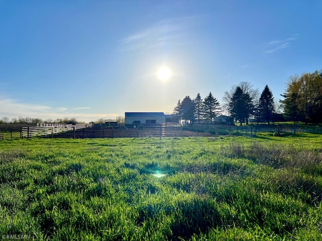 view of yard featuring an outbuilding, a rural view, fence, and a pole building