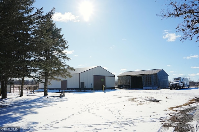 snow covered structure with an outbuilding