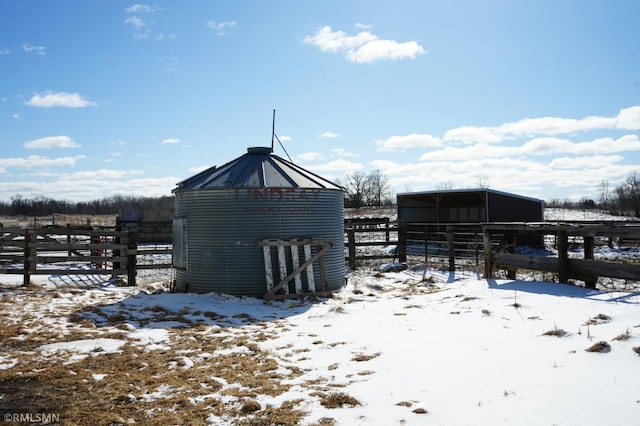 snow covered structure with an outbuilding