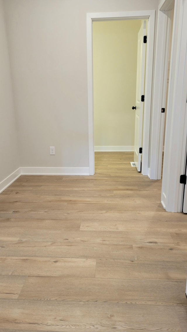 empty room with light wood finished floors and baseboards