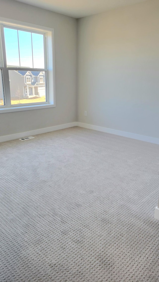 empty room with baseboards, visible vents, and carpet flooring