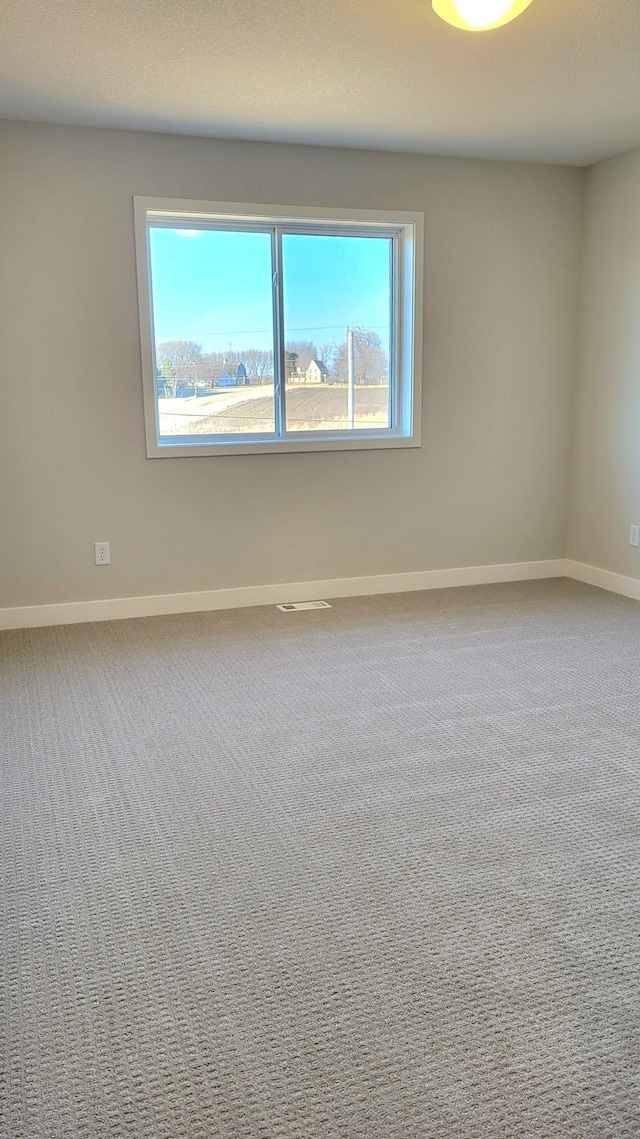 carpeted spare room with plenty of natural light and baseboards