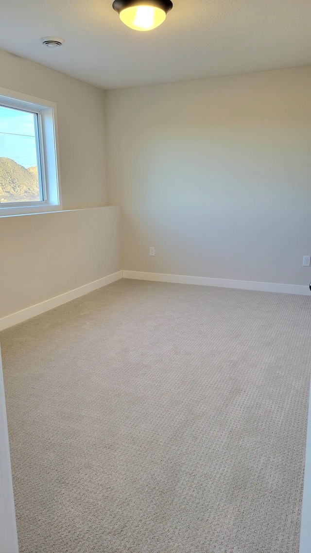 spare room with carpet floors, visible vents, and baseboards