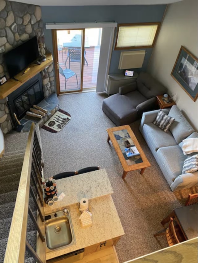 carpeted living area with stairs and a fireplace