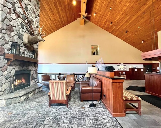 unfurnished living room with wood ceiling, high vaulted ceiling, and a stone fireplace