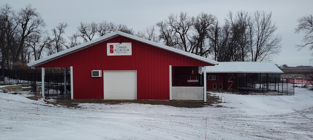 snow covered structure featuring an outdoor structure and fence