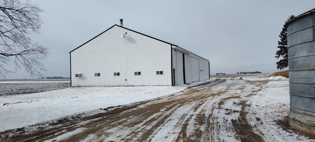 snow covered structure featuring an outbuilding and a pole building