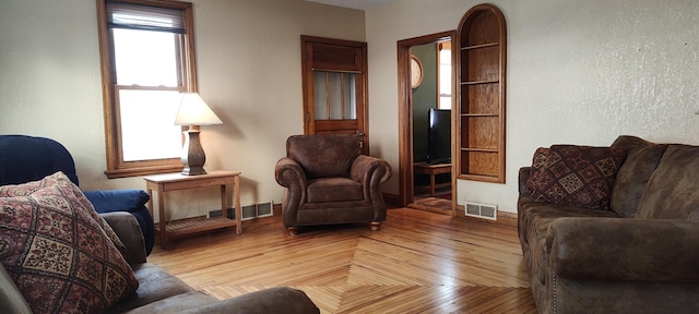 living area featuring visible vents and wood finished floors