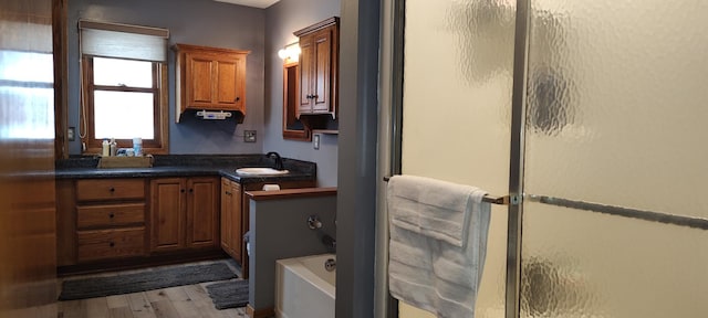 full bathroom featuring wood finished floors, an enclosed shower, vanity, and a tub