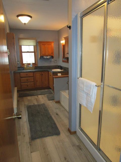 bathroom with a washtub, a stall shower, vanity, and wood finished floors