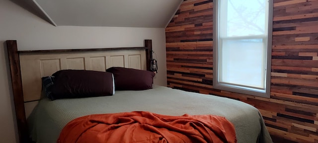 bedroom featuring lofted ceiling and wood walls