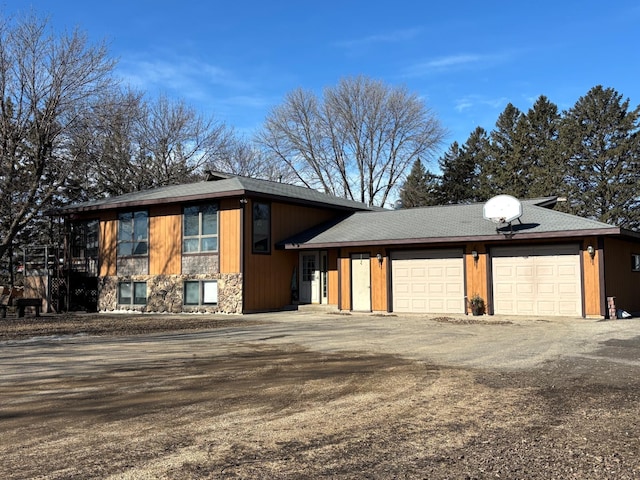 view of front of home with driveway, stone siding, and a garage