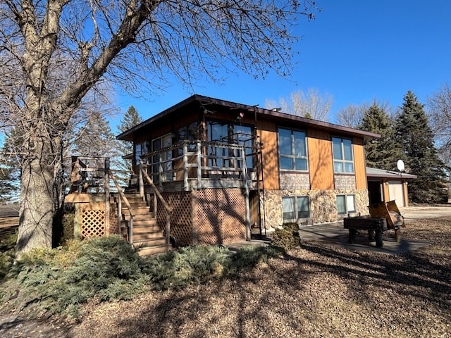 rear view of house with stone siding, stairway, a patio, and a wooden deck