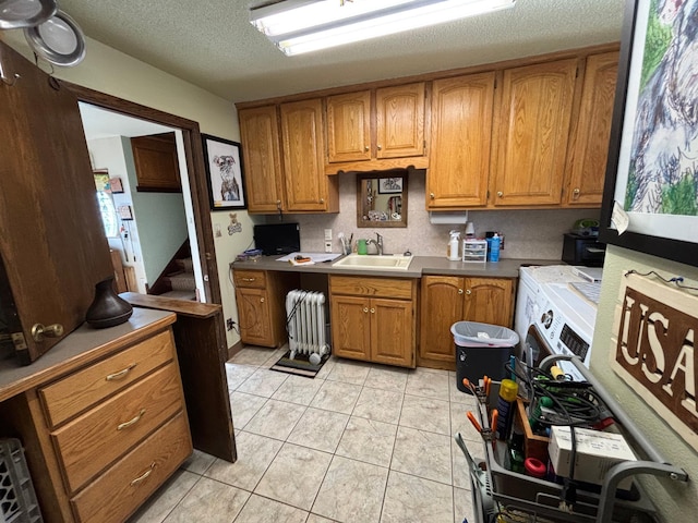 kitchen featuring independent washer and dryer, radiator, brown cabinets, and a sink