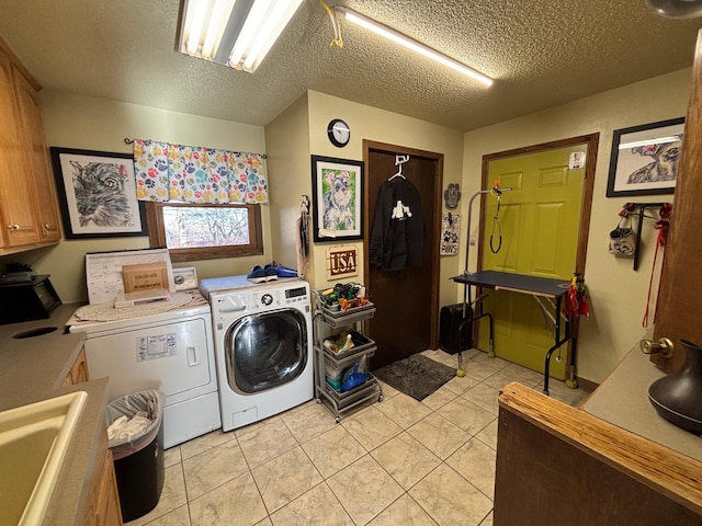 laundry room featuring a textured ceiling, light tile patterned floors, washing machine and dryer, a sink, and cabinet space