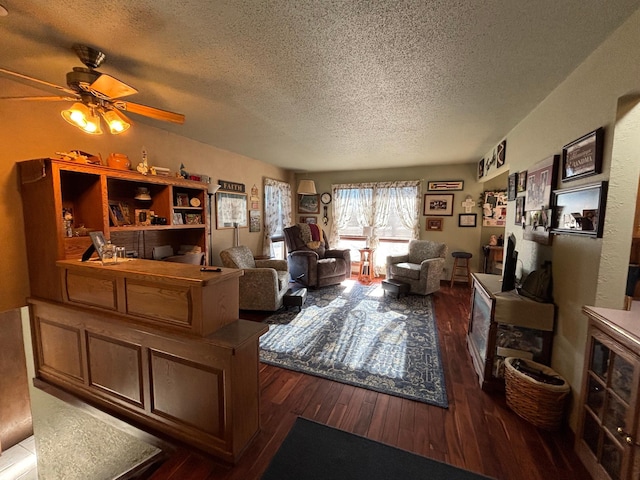 living area with a ceiling fan, a textured ceiling, and wood finished floors