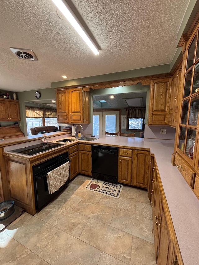 kitchen featuring black appliances, visible vents, brown cabinets, and light countertops