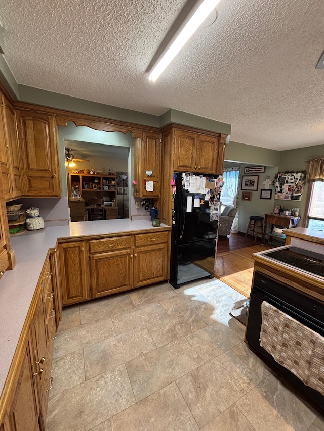 kitchen with light countertops, freestanding refrigerator, and brown cabinets