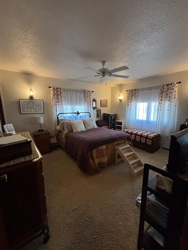 carpeted bedroom featuring a textured ceiling and a ceiling fan