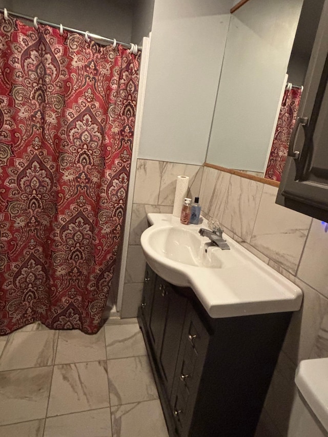 full bath with curtained shower, toilet, vanity, tile walls, and marble finish floor