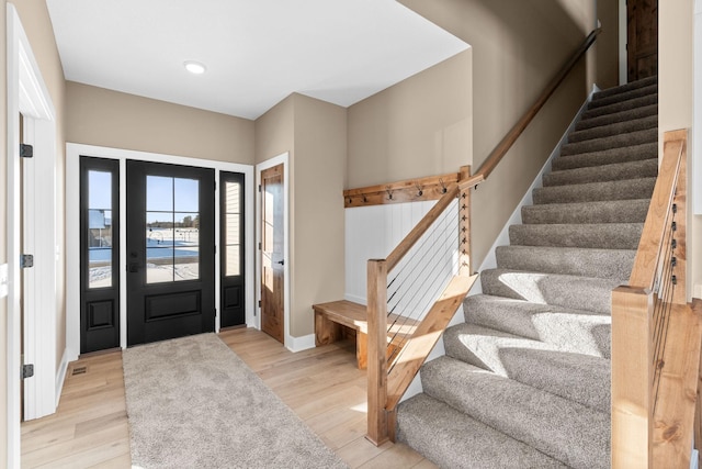 foyer featuring light wood finished floors, baseboards, and stairway