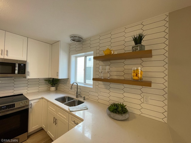 kitchen featuring electric range, a sink, light countertops, open shelves, and stainless steel microwave