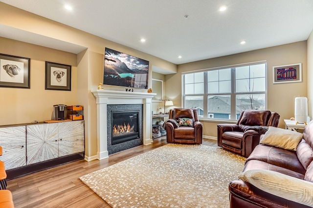 living room with a glass covered fireplace, baseboards, recessed lighting, and wood finished floors