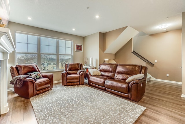 living room featuring light wood finished floors, stairway, baseboards, and recessed lighting