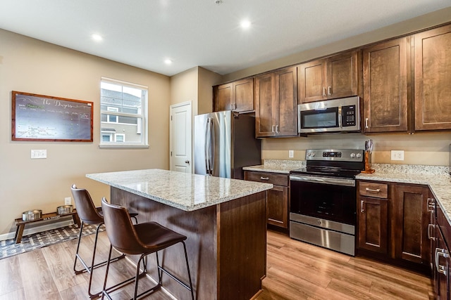 kitchen featuring light wood finished floors, a center island, stainless steel appliances, and a kitchen breakfast bar