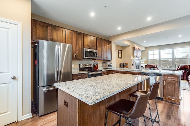 kitchen featuring a peninsula, light wood-style floors, a kitchen island, and stainless steel appliances