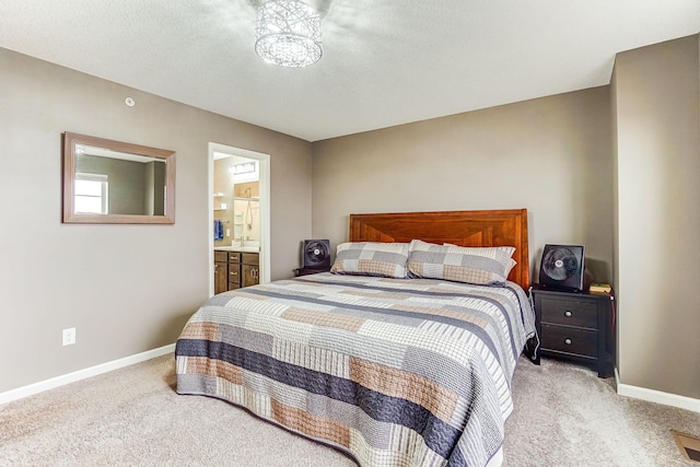 bedroom with baseboards, a textured ceiling, connected bathroom, and light colored carpet