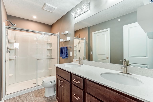 bathroom featuring toilet, a shower stall, double vanity, and a sink