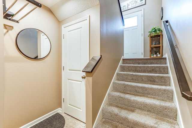 stairway featuring vaulted ceiling and baseboards