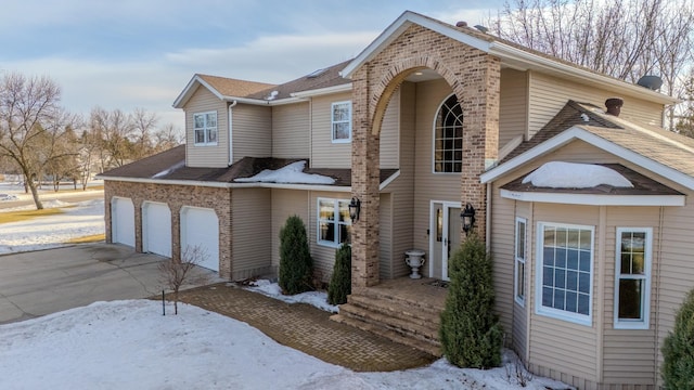 traditional-style home featuring a garage, concrete driveway, and brick siding