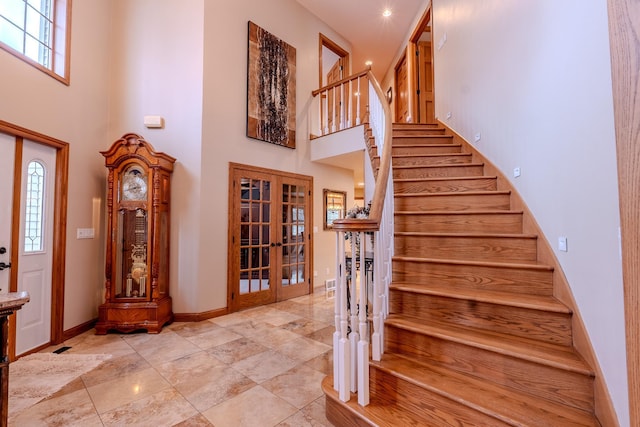 foyer entrance with french doors, baseboards, stairway, and a high ceiling