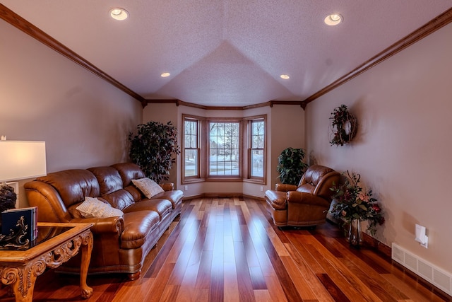 living room featuring a textured ceiling, wood finished floors, visible vents, and crown molding