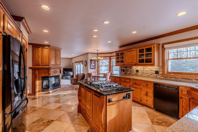 kitchen featuring brown cabinets, tasteful backsplash, a kitchen island, black appliances, and a multi sided fireplace