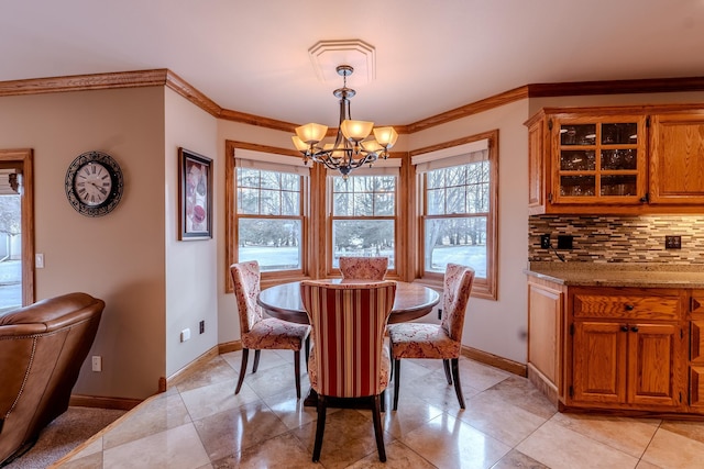 dining space featuring a chandelier, a healthy amount of sunlight, ornamental molding, and baseboards