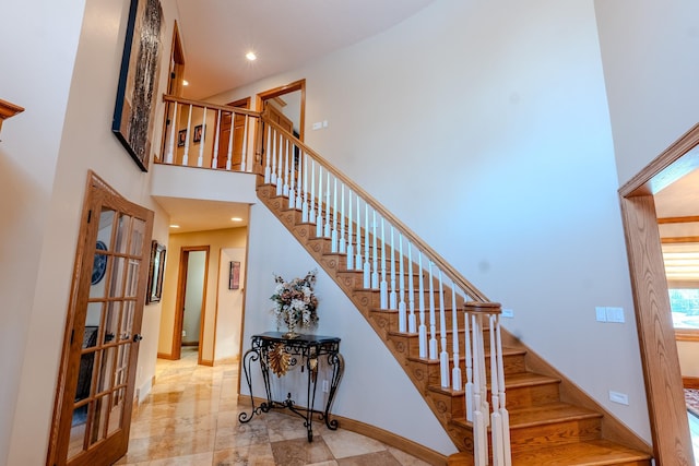 stairway featuring a towering ceiling, baseboards, and recessed lighting