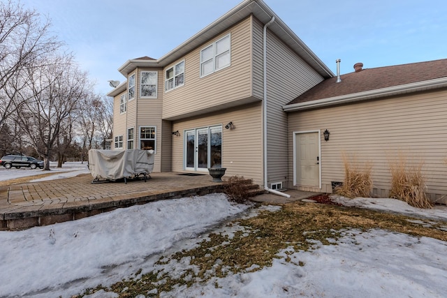 snow covered rear of property featuring a patio and french doors