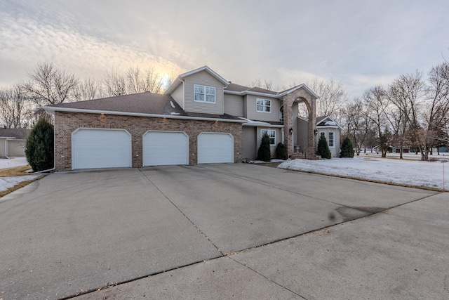 view of front facade with driveway, roof with shingles, a garage, and brick siding