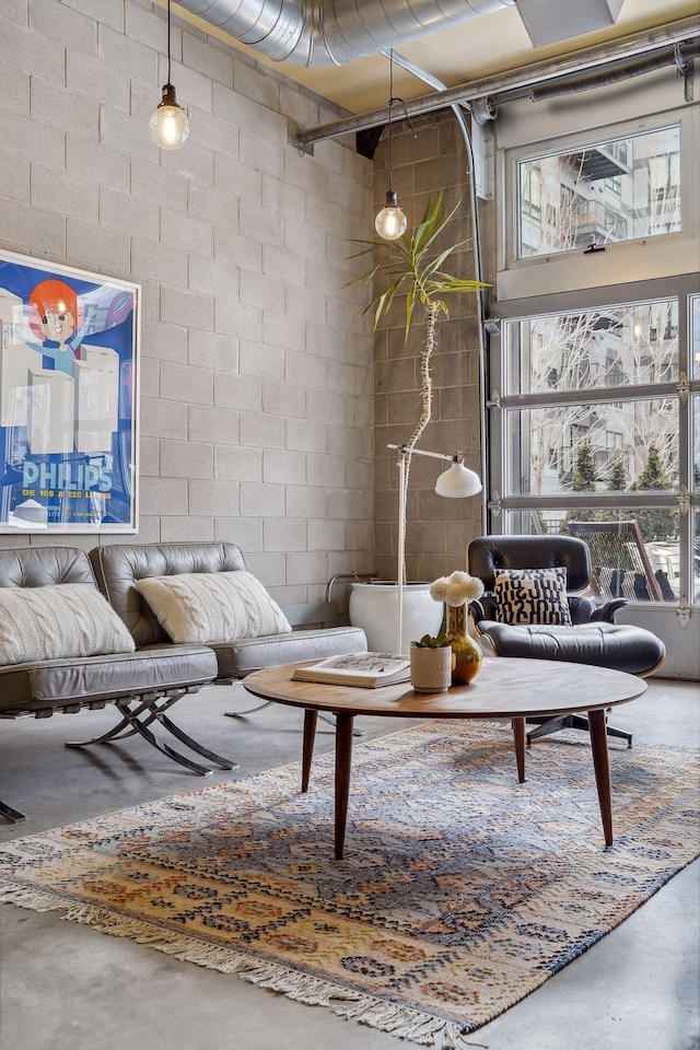 living area with finished concrete flooring and concrete block wall