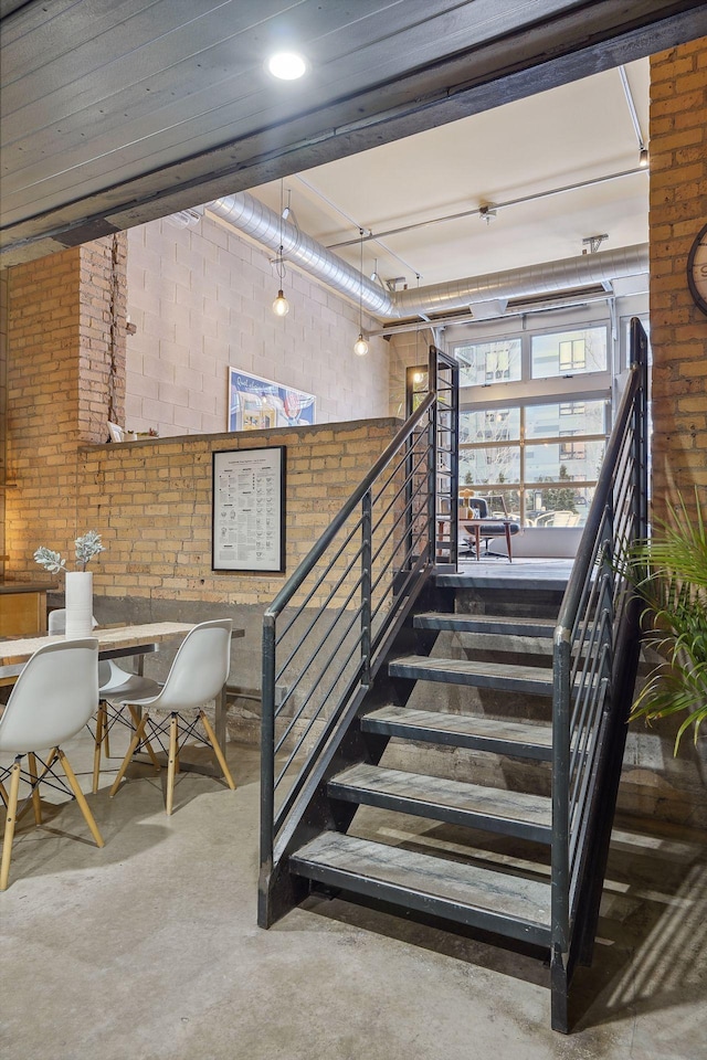 stairway featuring brick wall and concrete floors