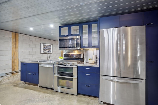 kitchen featuring light countertops, appliances with stainless steel finishes, a sink, blue cabinets, and concrete flooring