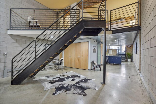 interior space with finished concrete flooring, a towering ceiling, and concrete block wall