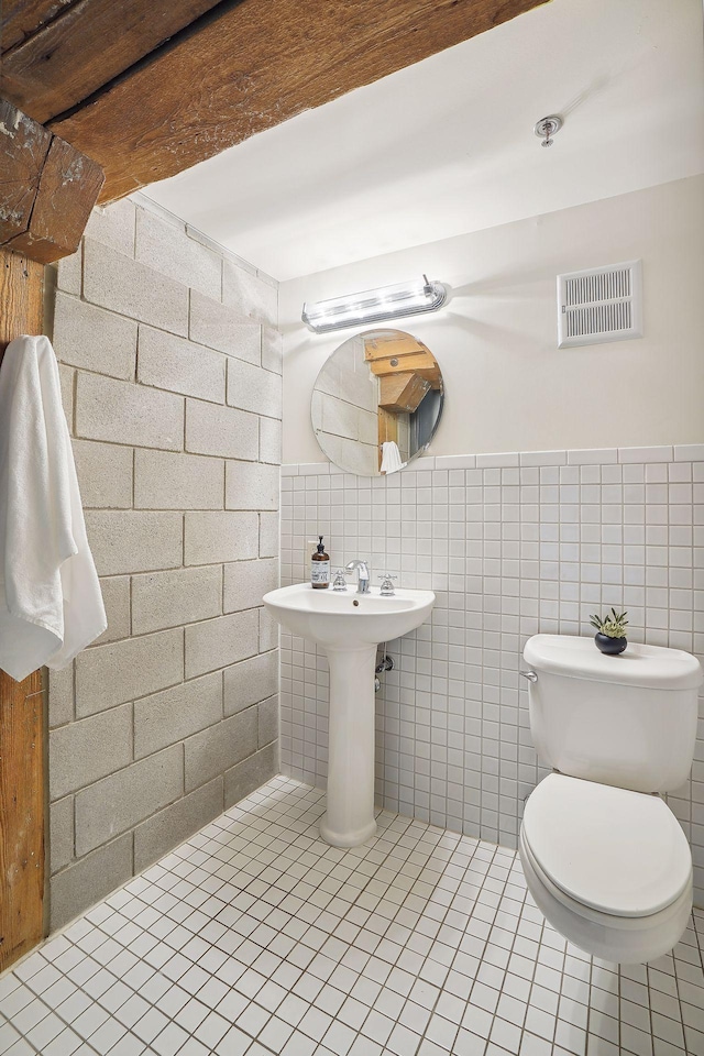 half bathroom featuring visible vents, tile walls, toilet, and tile patterned floors