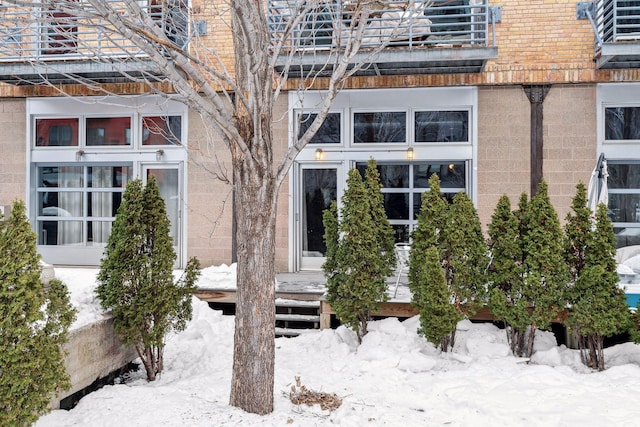 snow covered property entrance featuring brick siding