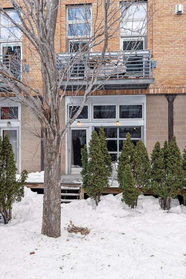 snow covered rear of property with brick siding