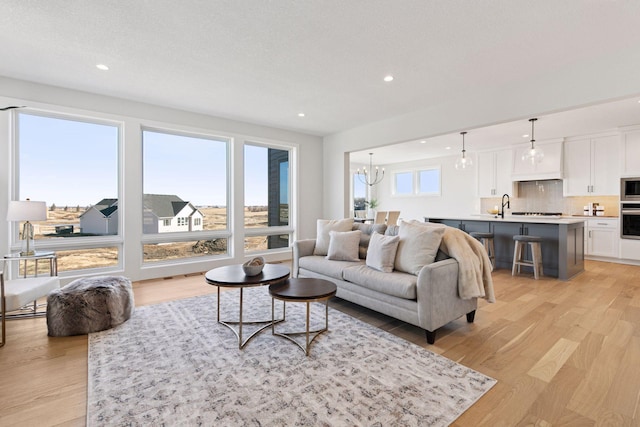 living area with an inviting chandelier, light wood-style flooring, and recessed lighting