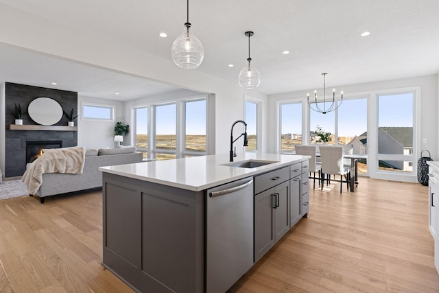 kitchen featuring gray cabinetry, a sink, light countertops, stainless steel dishwasher, and light wood-type flooring